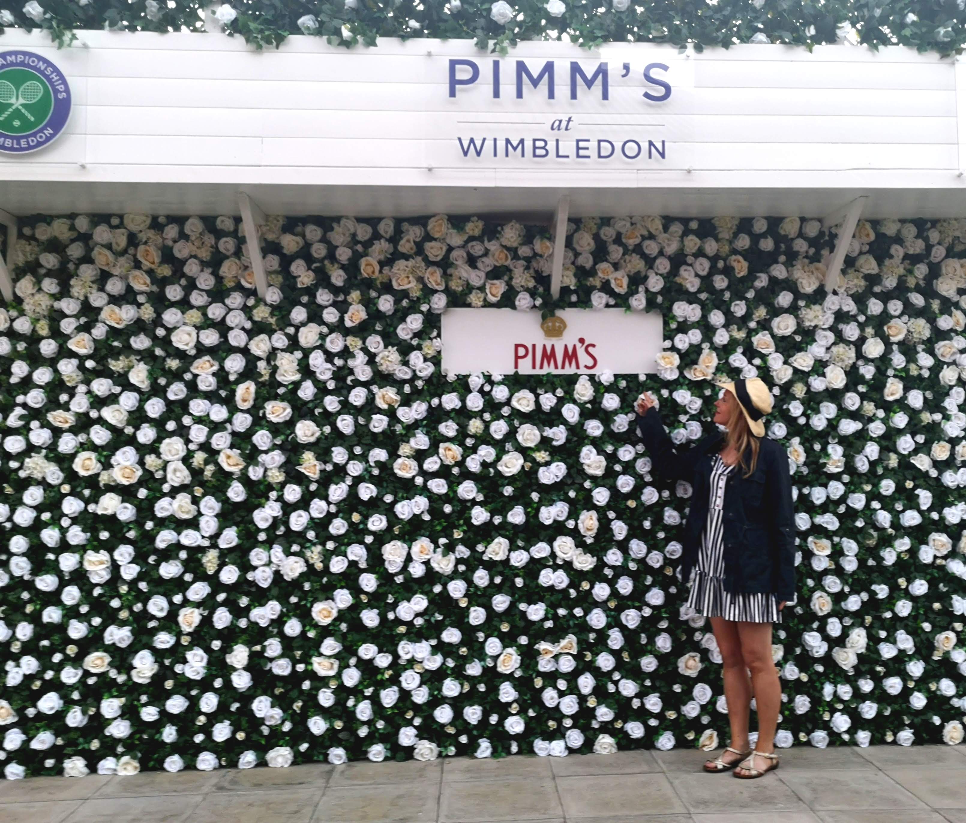Me stood by a flowery Pimms branded wall at Wimbledon
