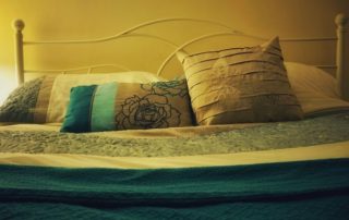 Bed with cushions in teal and bronze